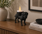 Bordeauxdog waxinelichthouder in zwarte kleur op houten dressoir met brandend kaarslicht en woondecoratie eromheen.