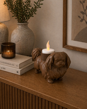 Matte bruine Pekingees hond waxinelichthouder met LED-waxinelichtje op houten kast in gezellige huiselijke setting.