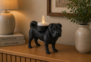 Zwarte Shar Pei hond waxinelichthouder op houten kast met warme verlichting in modern interieur.