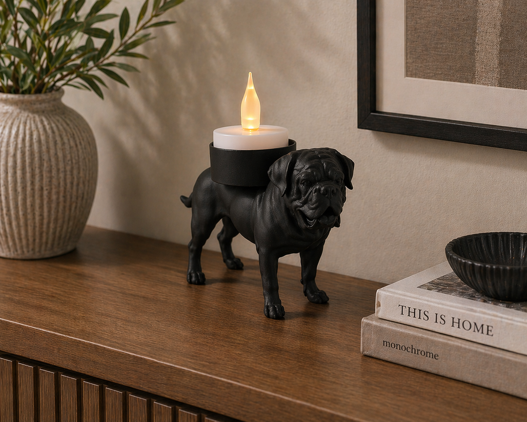 Bordeauxdog waxinelichthouder in zwarte kleur op houten dressoir met brandend kaarslicht en woondecoratie eromheen.