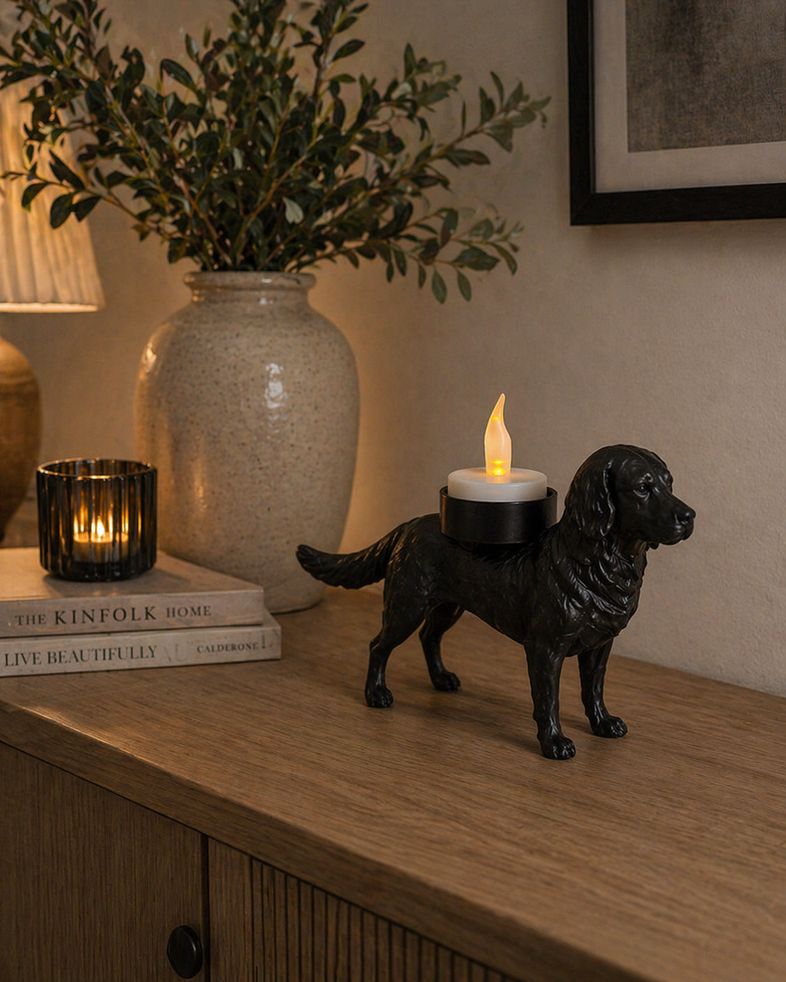 Zwarte Grote Münsterländer hond waxinelichthouder met led-waxinelichtje op een kastje langs de wand in stijlvolle woonruimte met decoratieve vaas en sfeerverlichting.