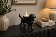 Zwarte Italiaanse Waterhond Lagotto Romagnolo waxinelichthouder met brandend LED-waxinelichtje op een zwart dressoir in warme huiselijke woonkamer.