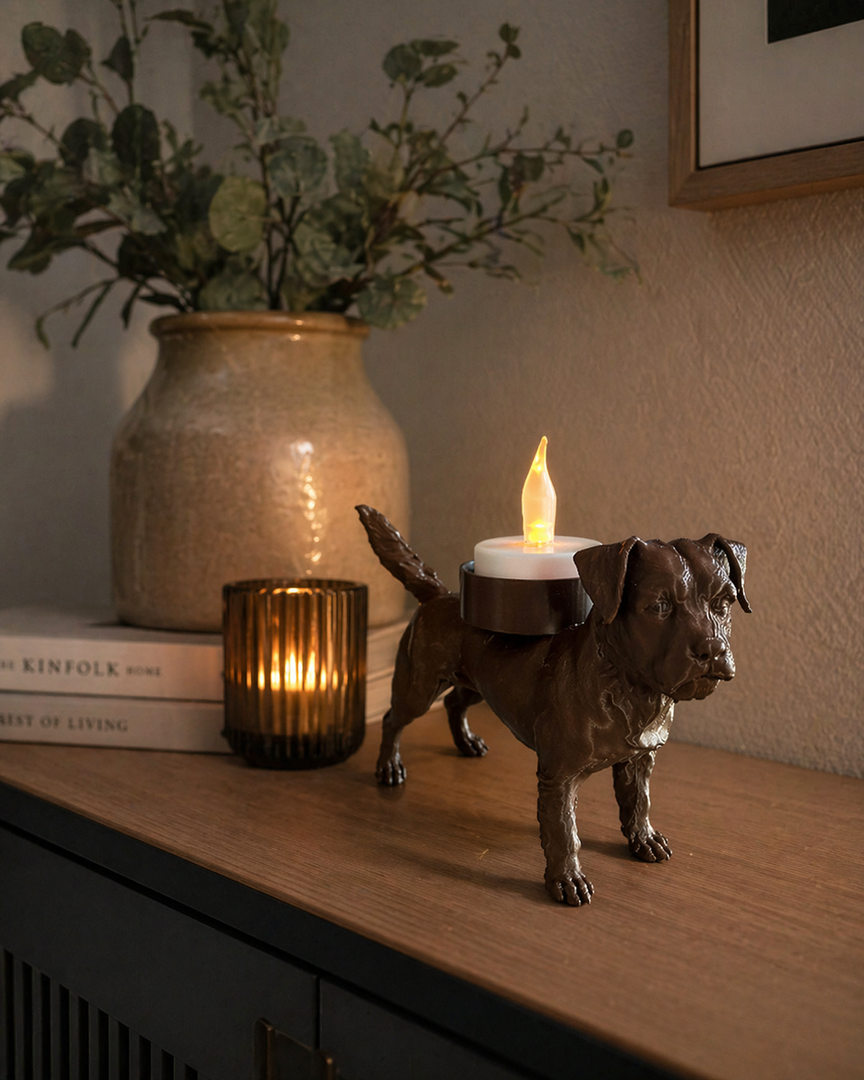 Bruine Waxinelichthouder Border Terrier met led-waxinelichtje op een houten kastje in warme huiselijke omgeving met vaas en kaarslicht.
