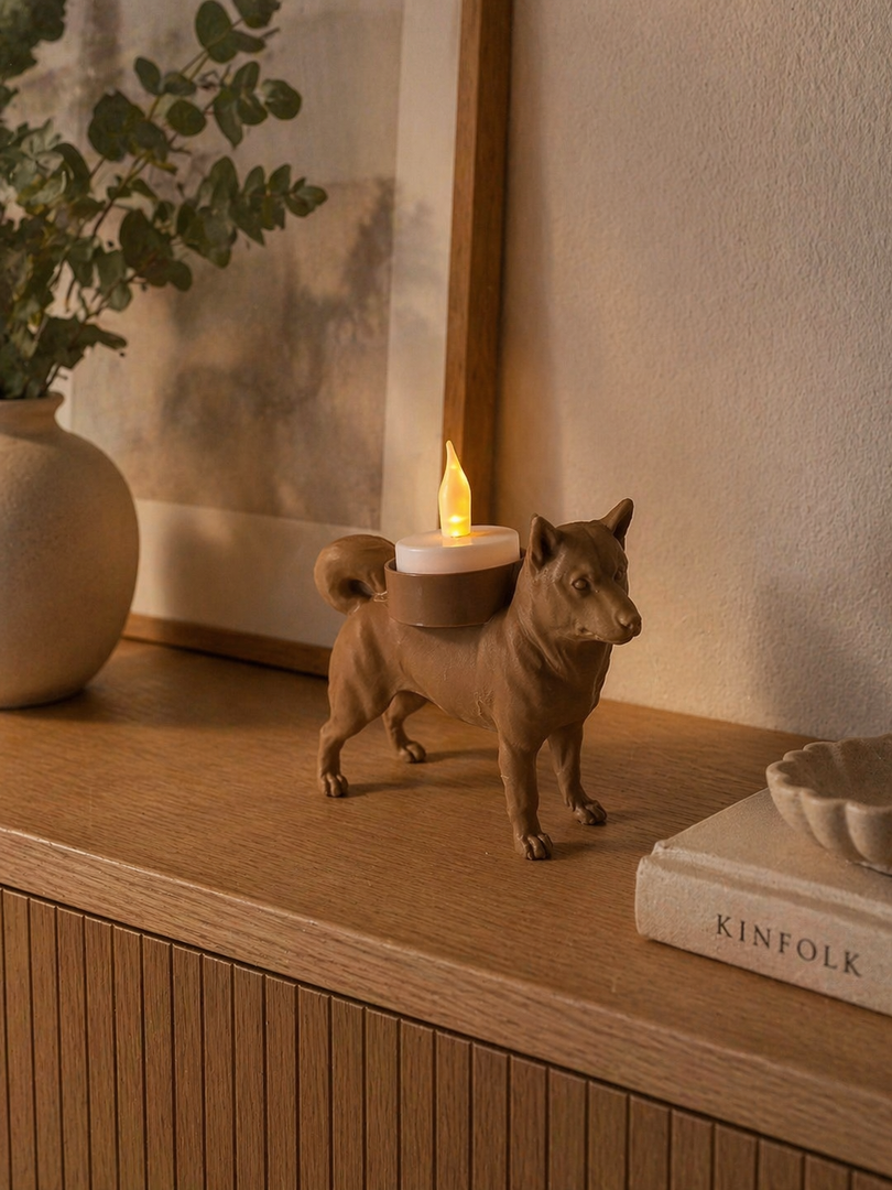 Bruine Shiba Inu waxinelichthouder met LED-waxinelichtje op houten kastje in gezellige woonruimte met wanddecoratie.
