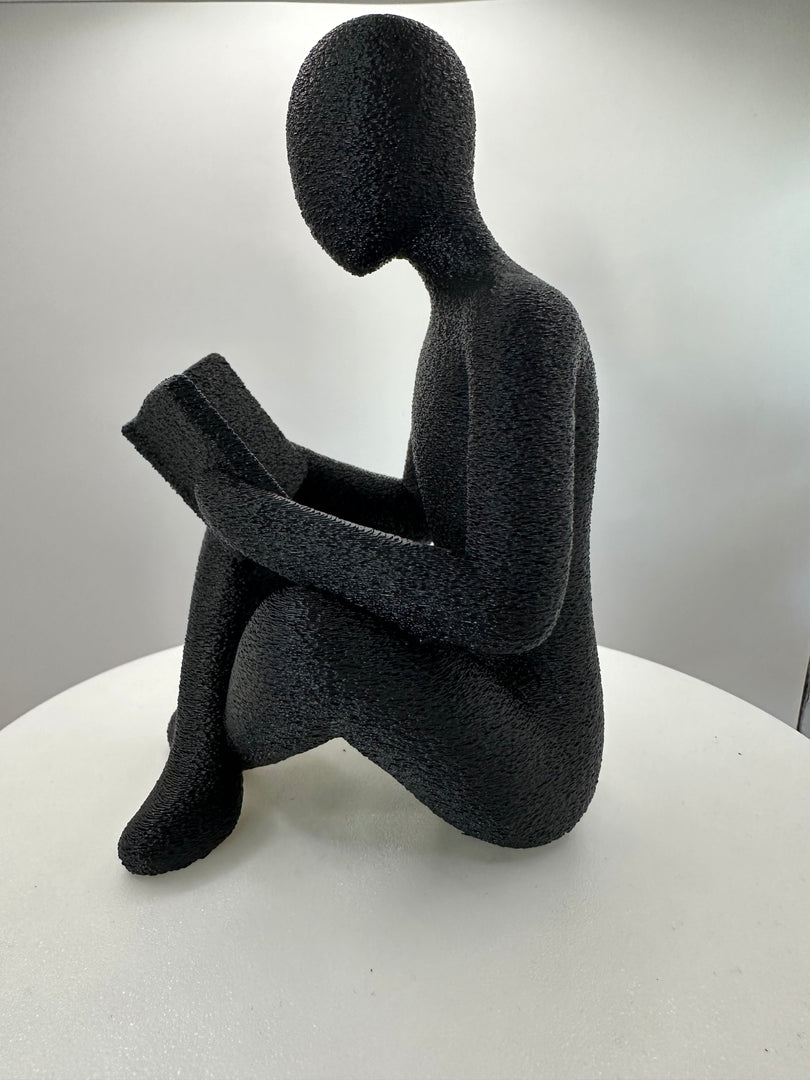 Detailfoto van een modern zwart decoratiebeeld van een lezende persoon met boek