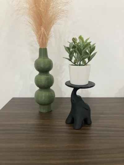 Stijlvol beeld van een olifant in majestueuze houding op een stevige standaard, geschikt als kaarshouder of plantenstandaard.